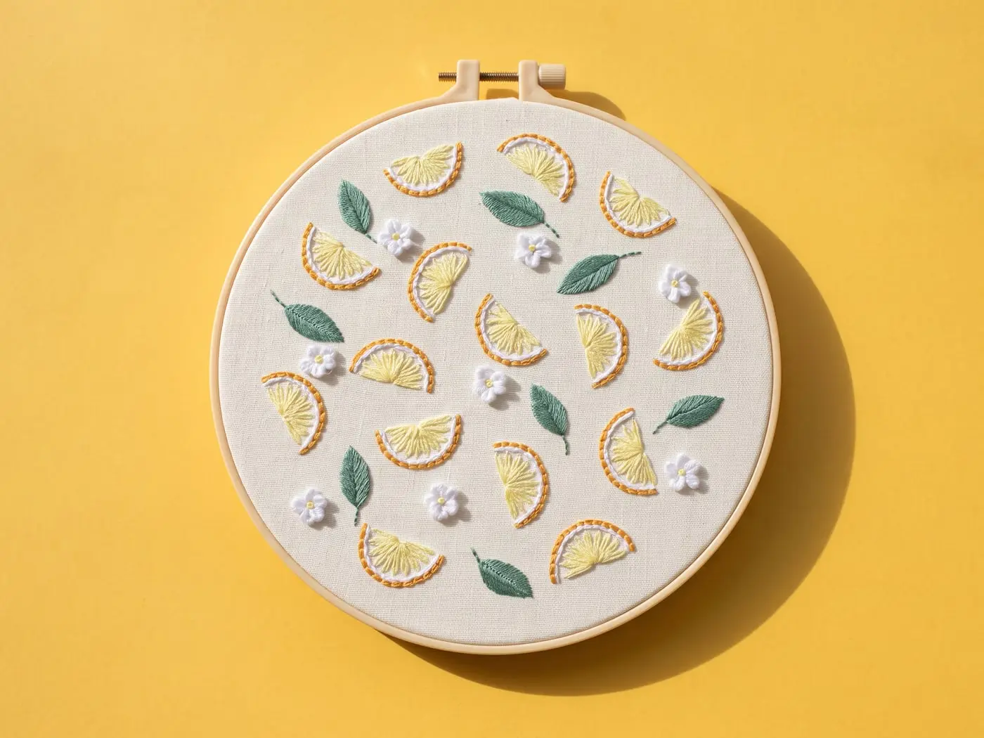 Tambour brodé de tranches de citron jaunes et de petites feuilles, posé sur un papier mimosa